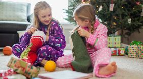 Two girls in pajamas opening their stockings
