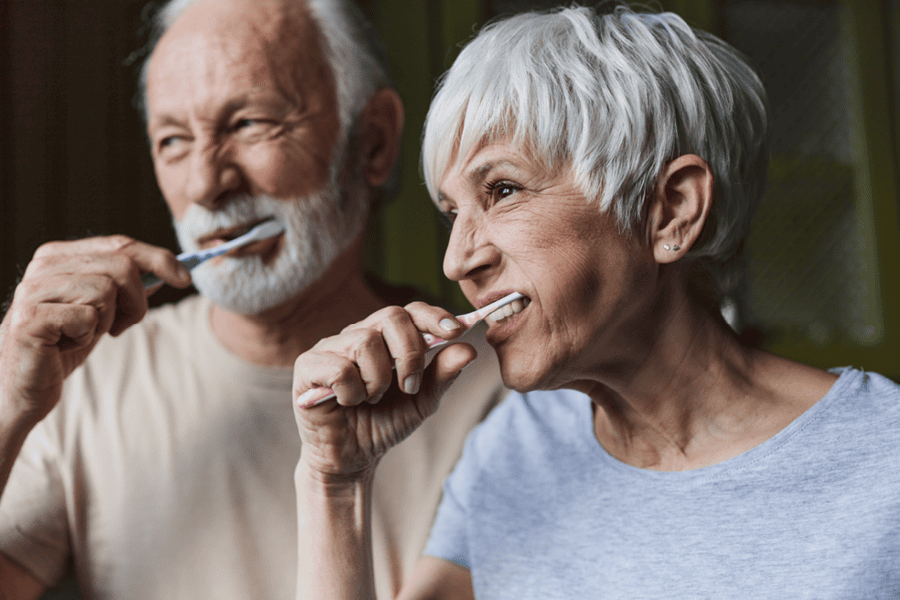 Older couple brushing their teeth together.