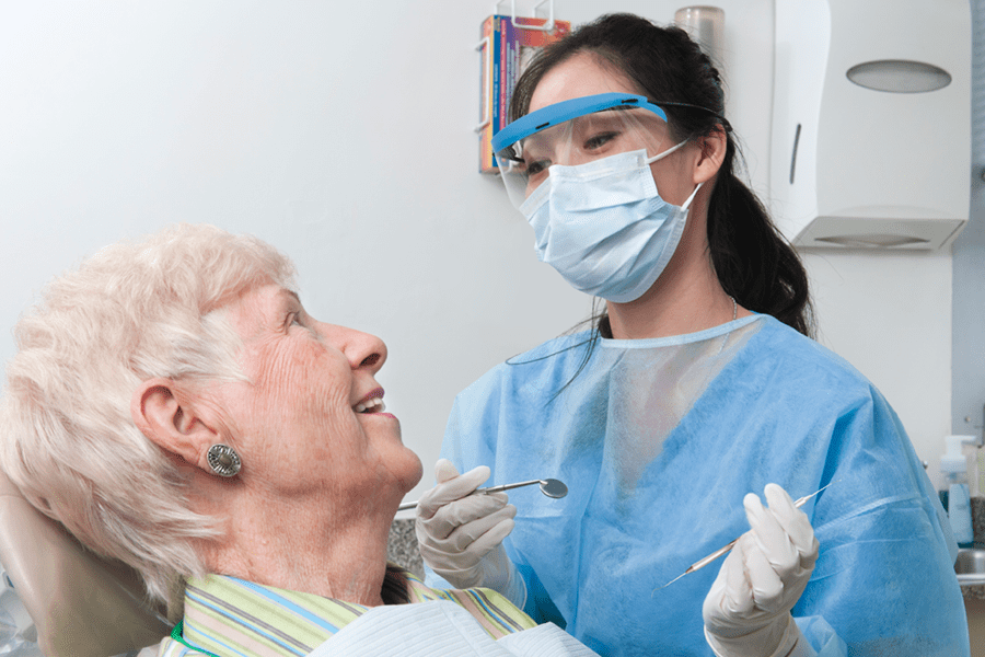 Dentist performing an oral health checkup on an older adult.
